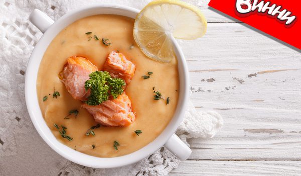 Salmon cream soup with lemon in a white bowl on the table. horizontal top view